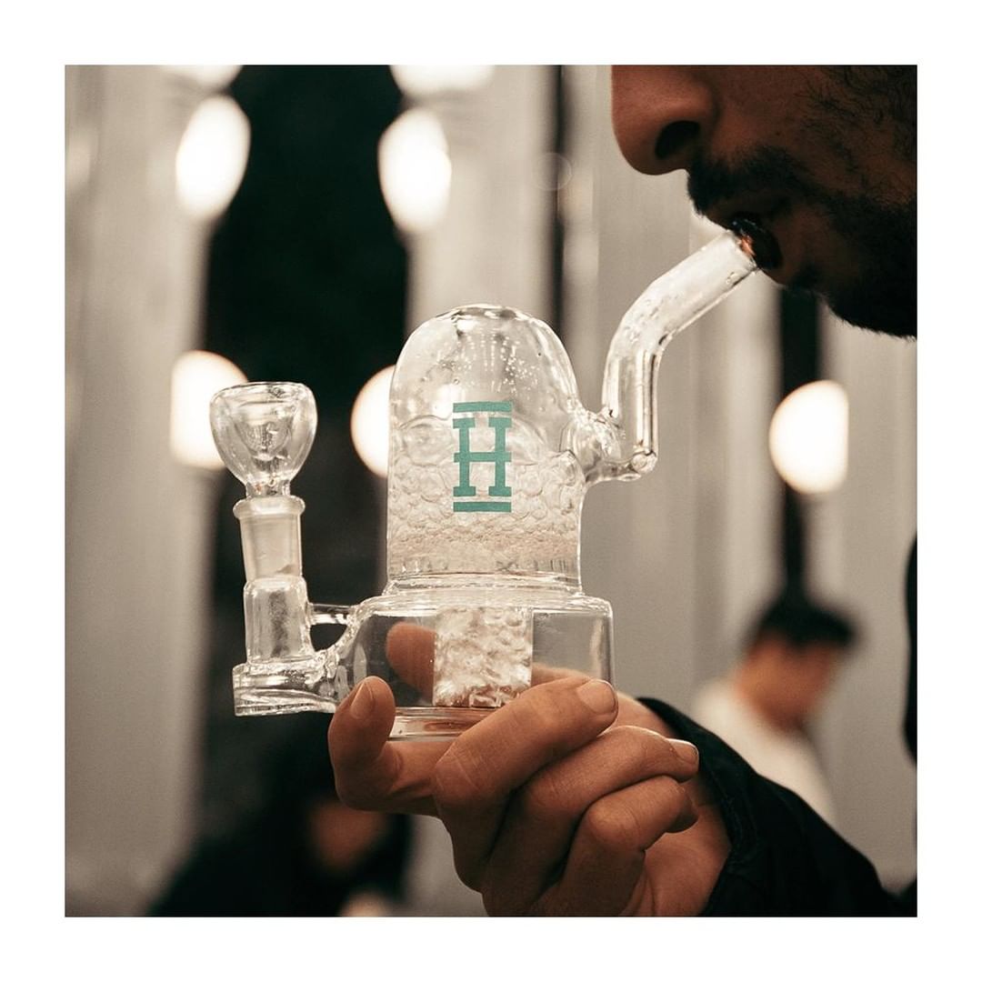 Person using Hemper Bell Rig bong in teal color with a deep bowl and 14mm joint size