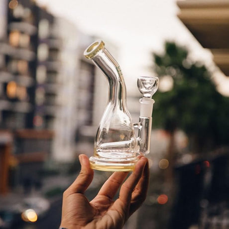 Hemper Inline Rig held in hand with city background, clear glass, 7" with in-line percolator