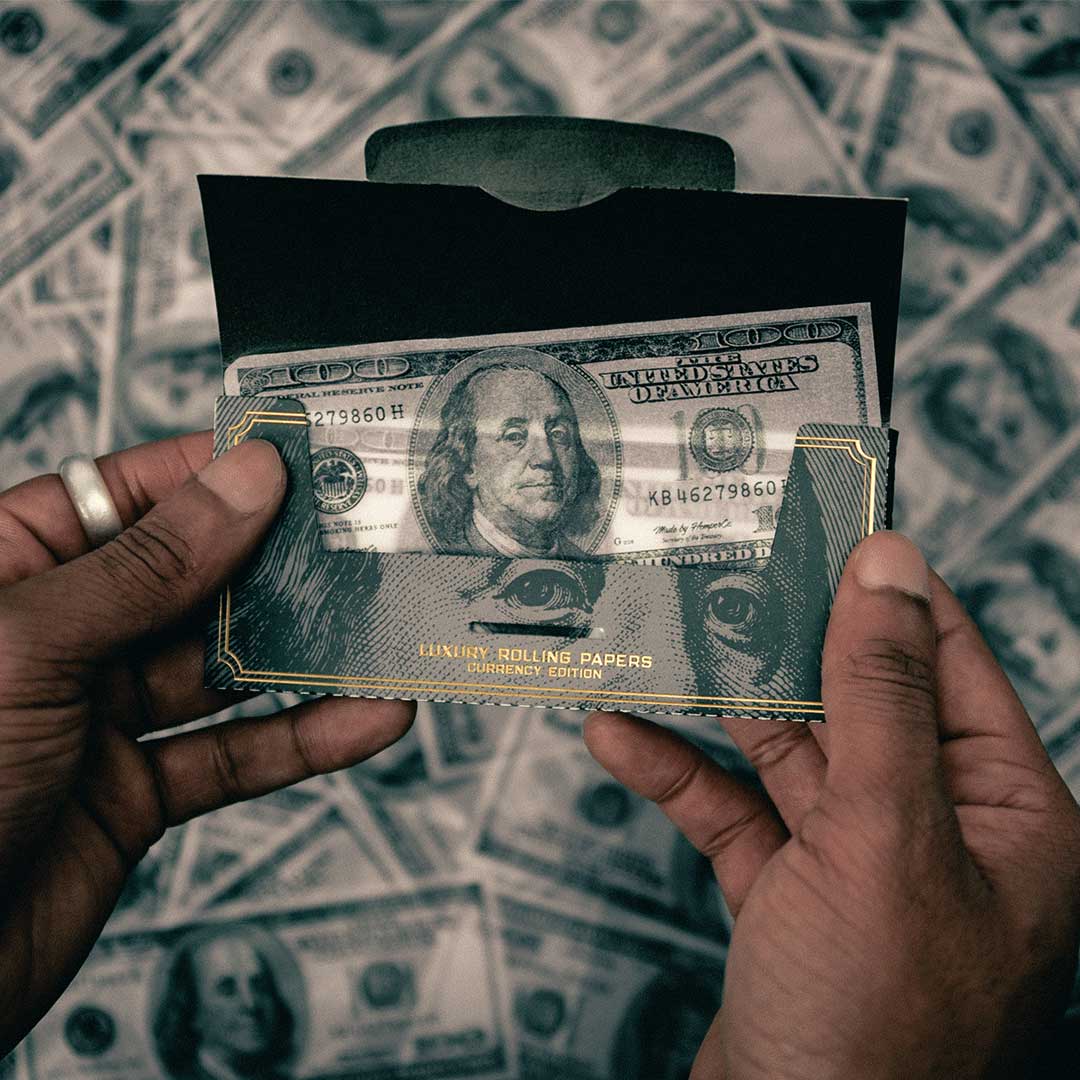 Hemper Notes Hemp Rolling Papers pack resembling a stack of $100 bills in hand
