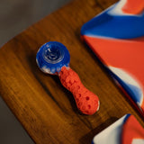 PILOT DIARY Silicone Pipe with Glass Bowl, Red and Blue, Angled View on Wooden Surface