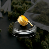 StonerDays exclusive Dab Bucket pin with gold finish on dark background, surrounded by cannabis buds