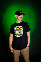 Man wearing StonerDays Stay Stoned Save Lives black cotton t-shirt, front view on green background